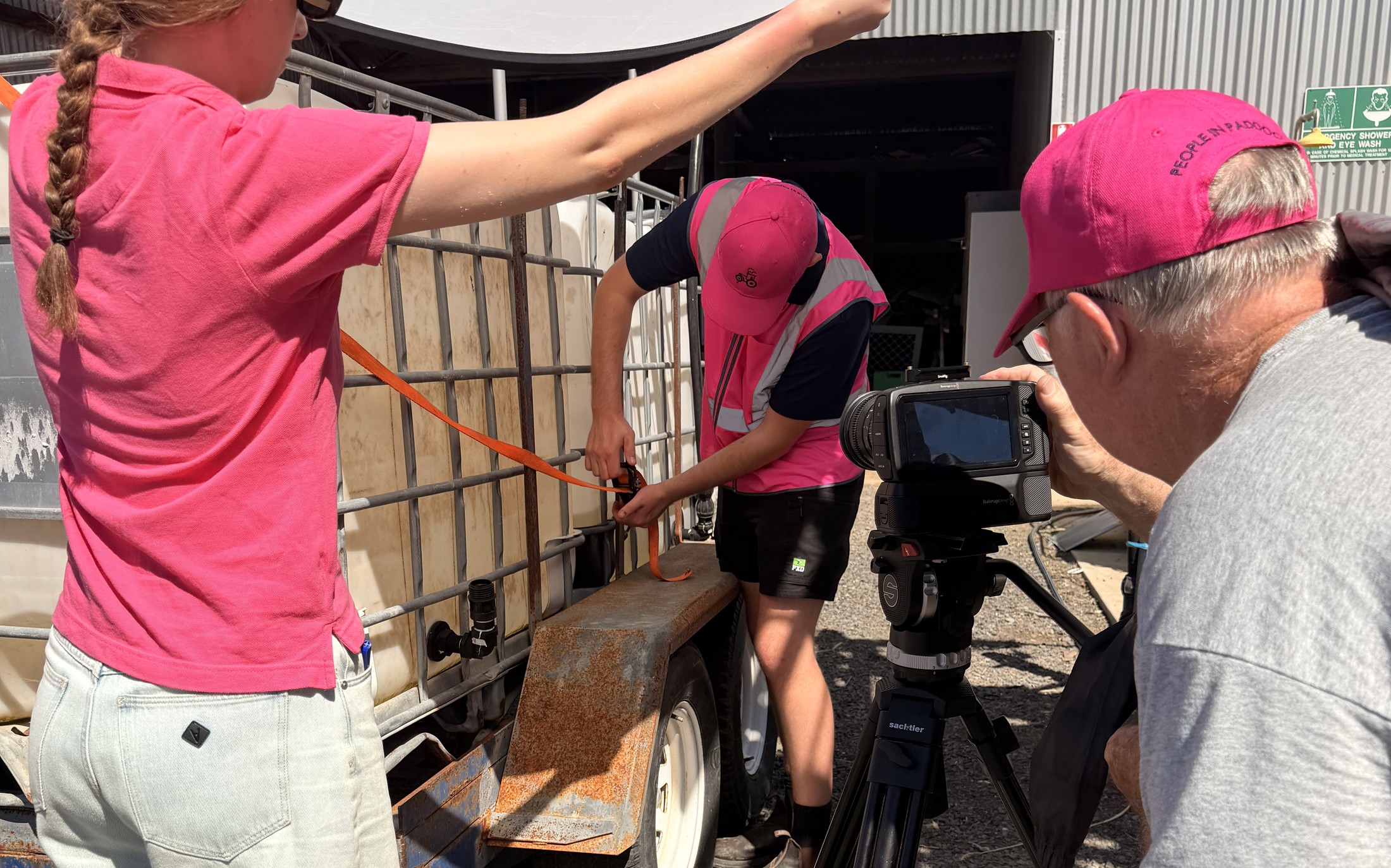 Behind the scenes filming Safety Served Sweet at Longerenong College: camera crew and a worker securing a tank strap, faces turned away from the camera